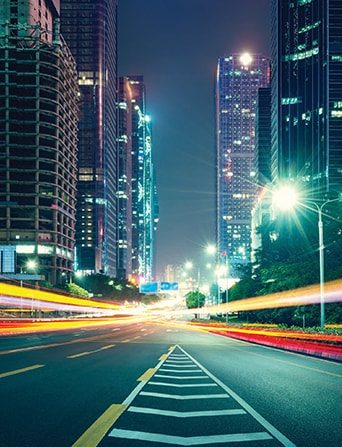 A busy road located in the centre of a thriving, lit-up city.