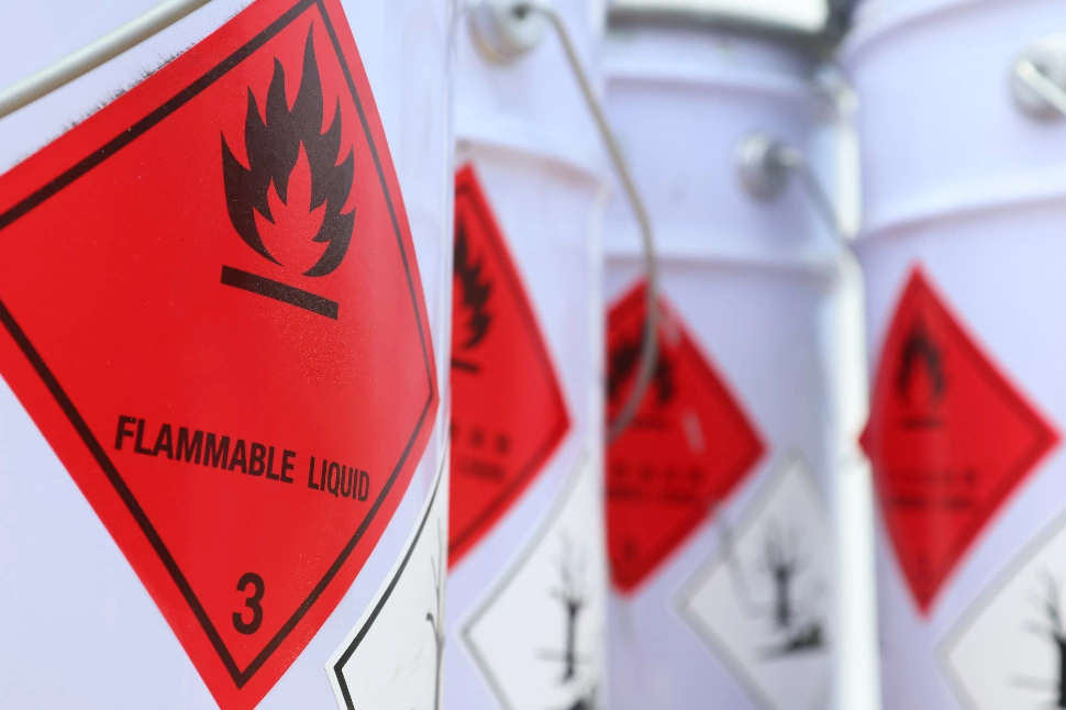 A collection of white containers featuring red warning labels marking the contents as flammable liquid.