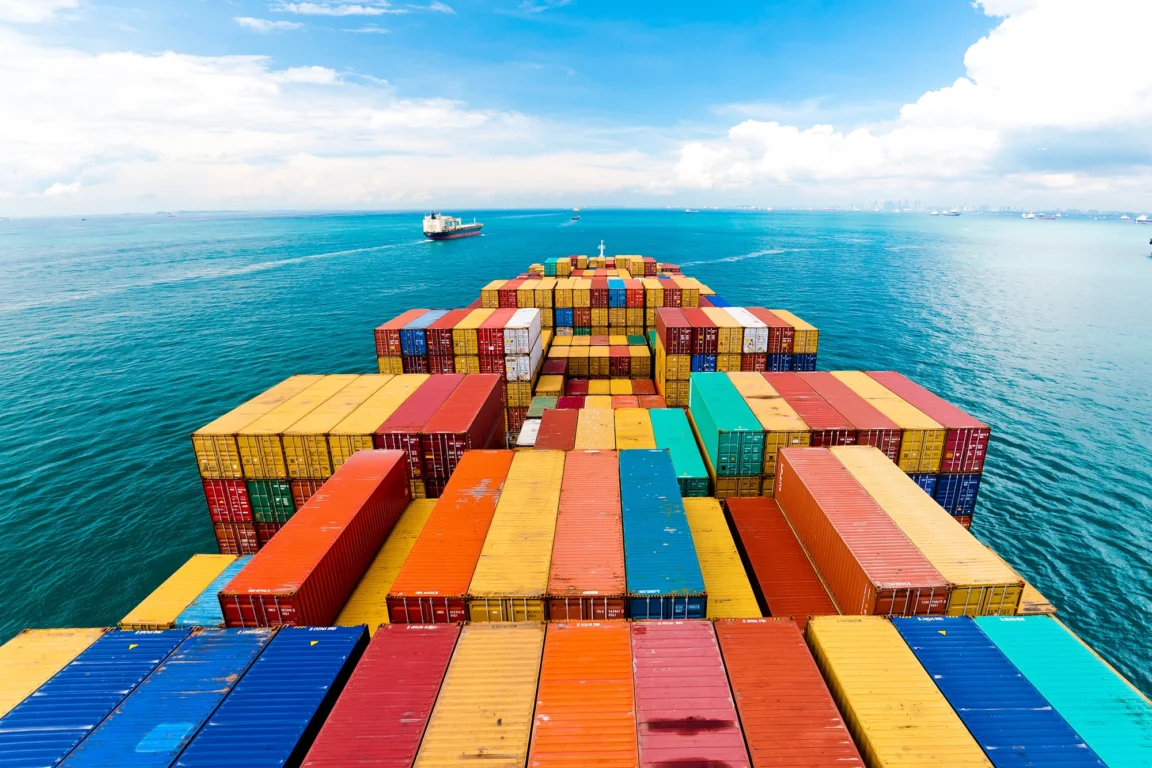 The deck of a cargo ship covered in colourful containers out at sea. 